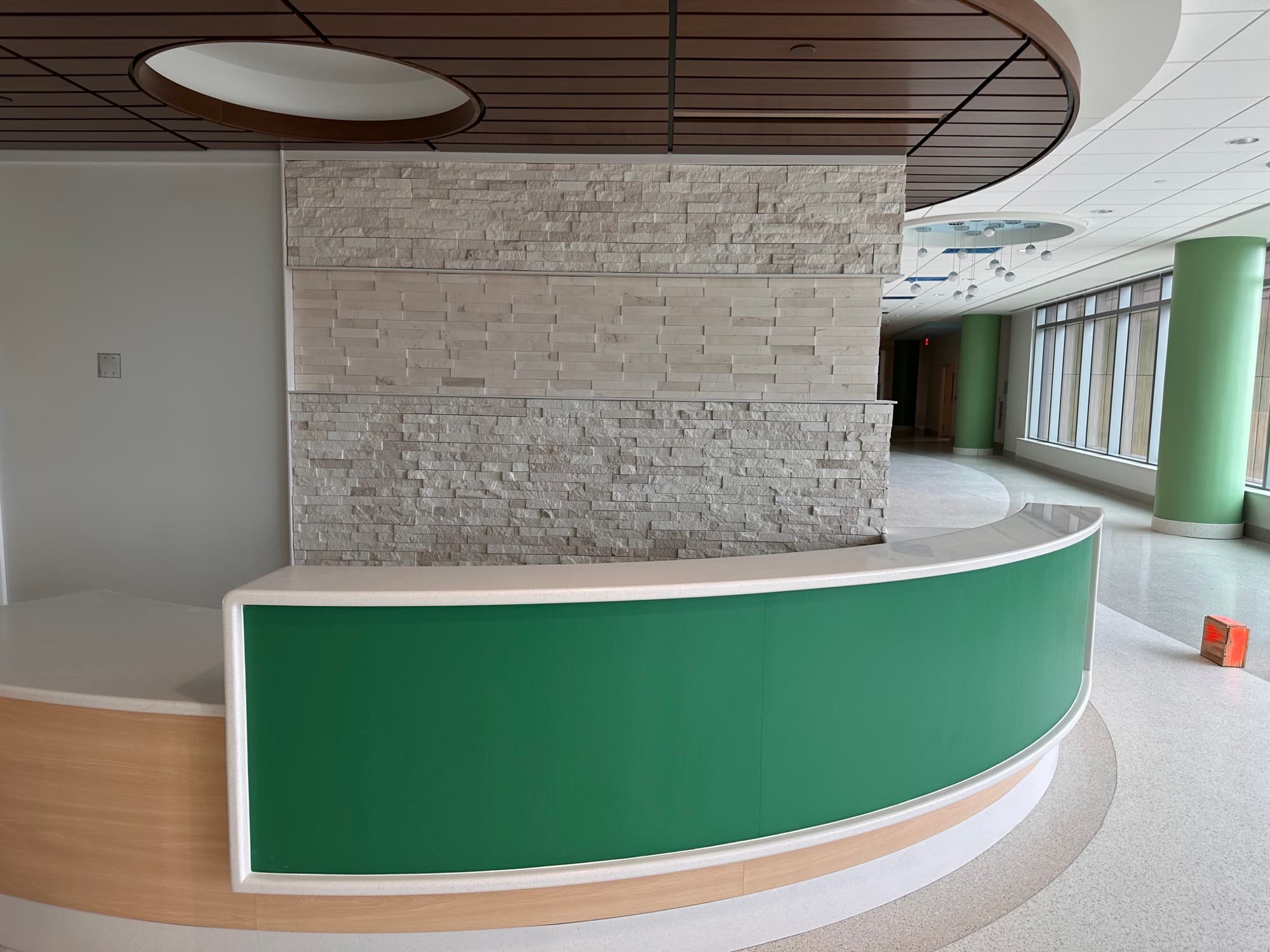 Completed commercial lobby with a curved reception desk and dimensional stone feature wall
