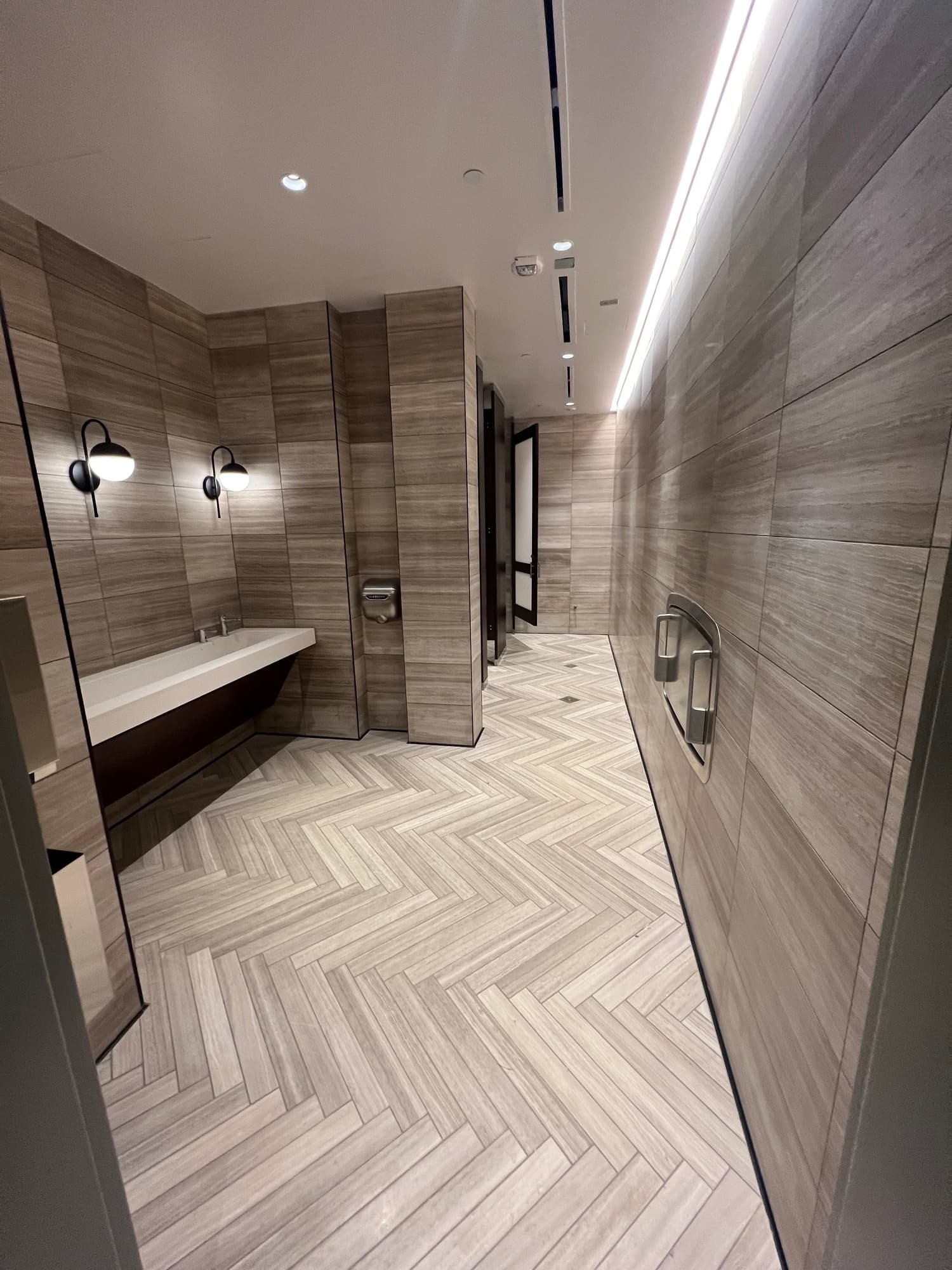 Completed commercial wet area with coordinated wall tile and a herringbone-pattern tile floor
